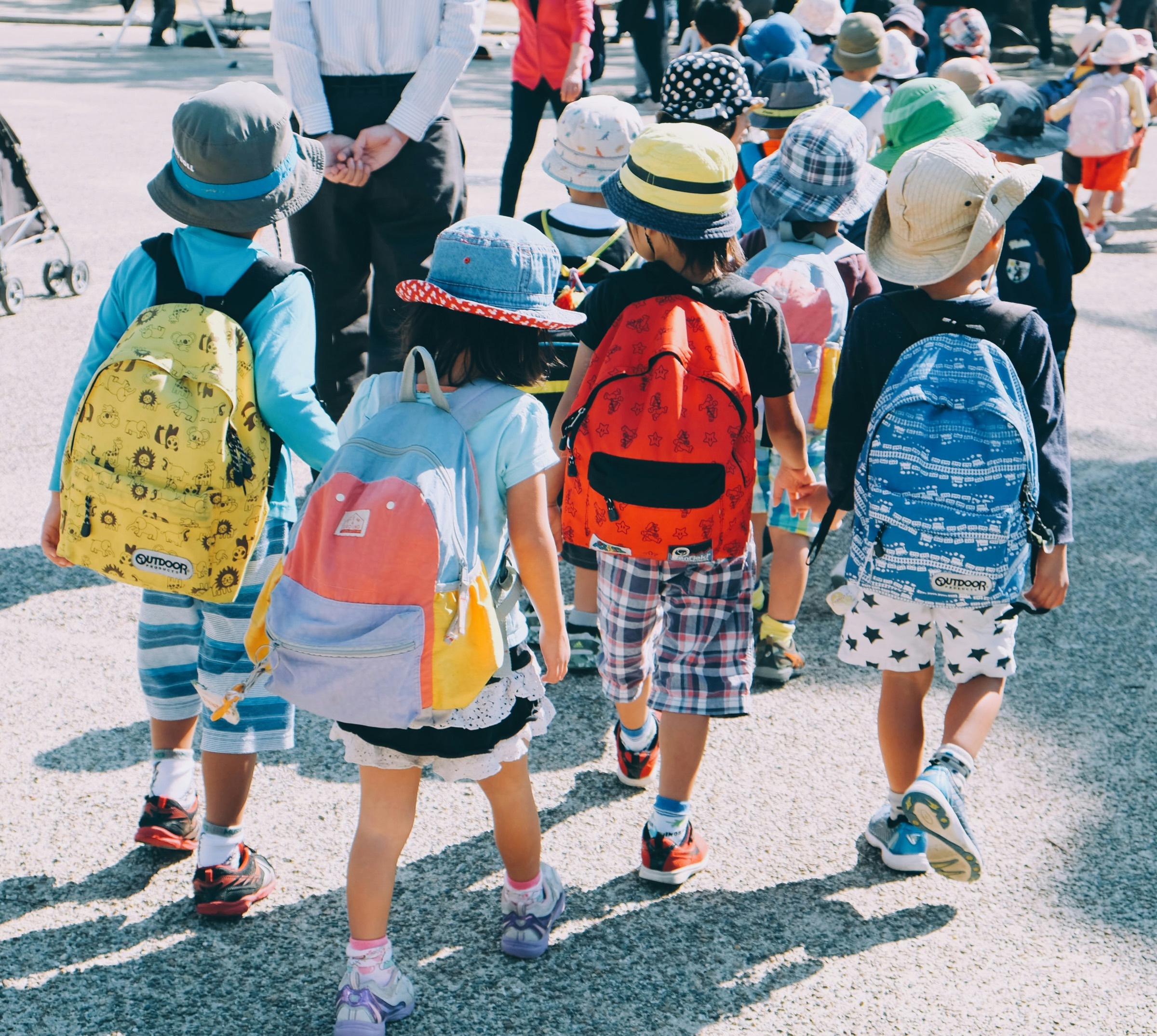 Young children with colourful backpacks walking to school together